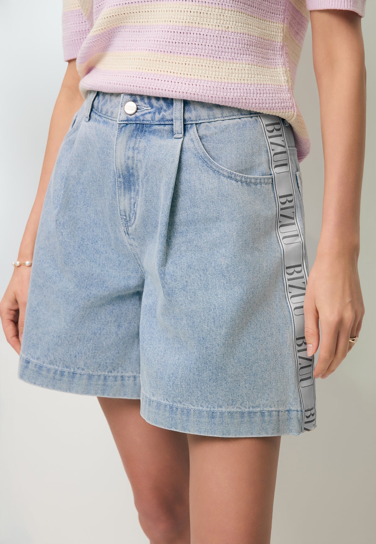 Close-up of the MIREYA denim shorts with a logo tape on the side.