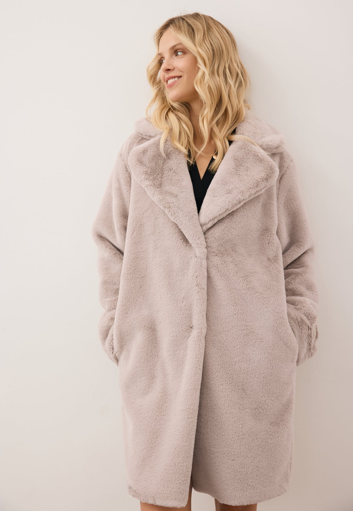 Model facing forward, dressed in the beige ROMA faux fur coat in a thigh-length cut with embossed sleeve logo.