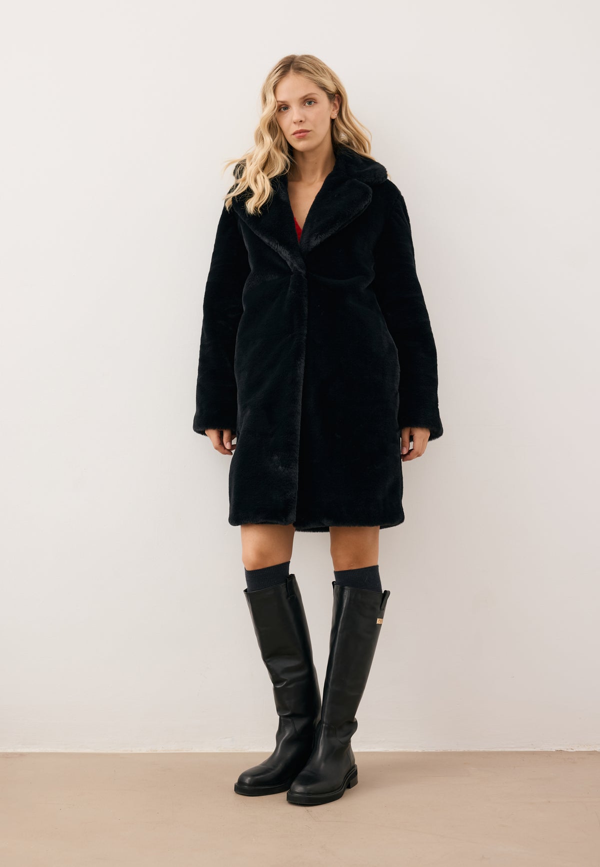 Model facing forward, wearing the black ROMA faux fur coat with embossed logo on the sleeve.