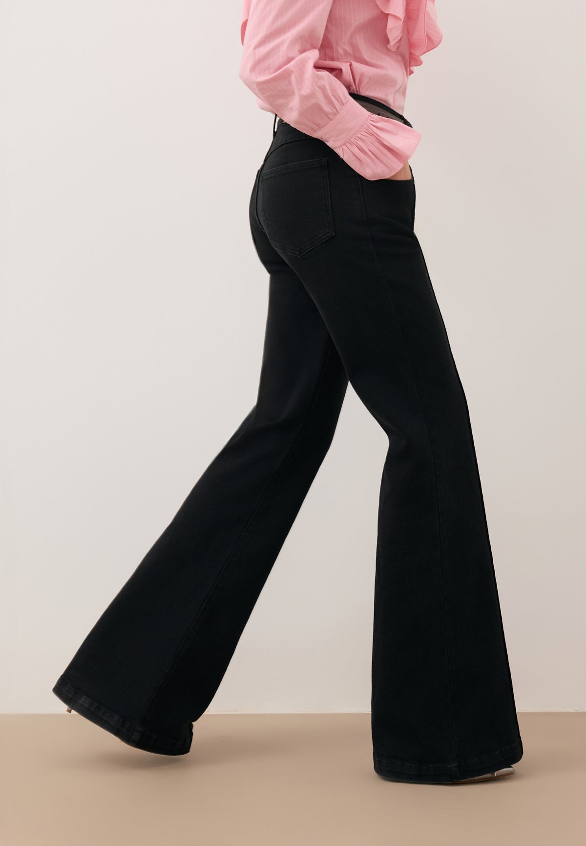 Close-up of the legs of a model stepping forward in black BELINNA flare jeans.