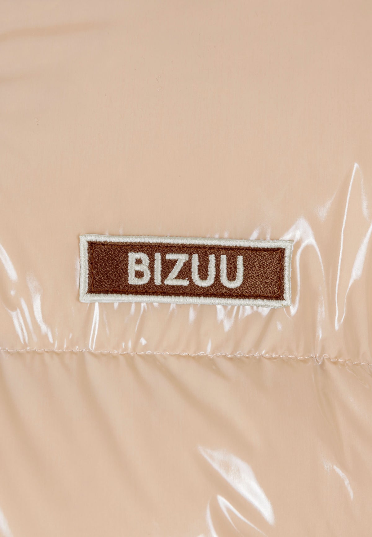 Close-up of the logo on the beige SANYA jacket.