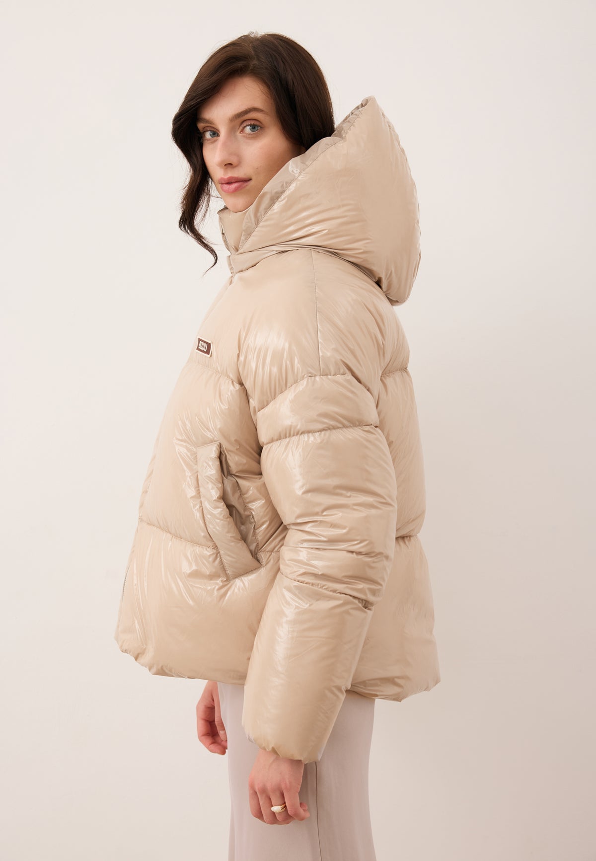 Model standing sideways wearing the beige SANYA puffer jacket.