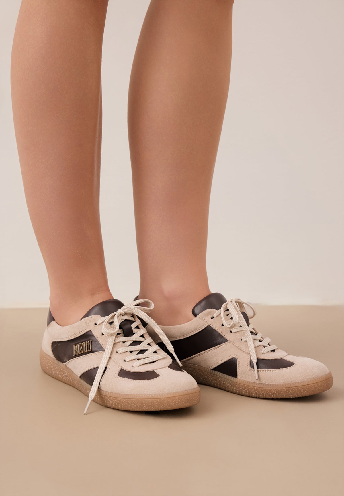 Close-up of the model's legs in beige SODDY sneakers with brown inserts.