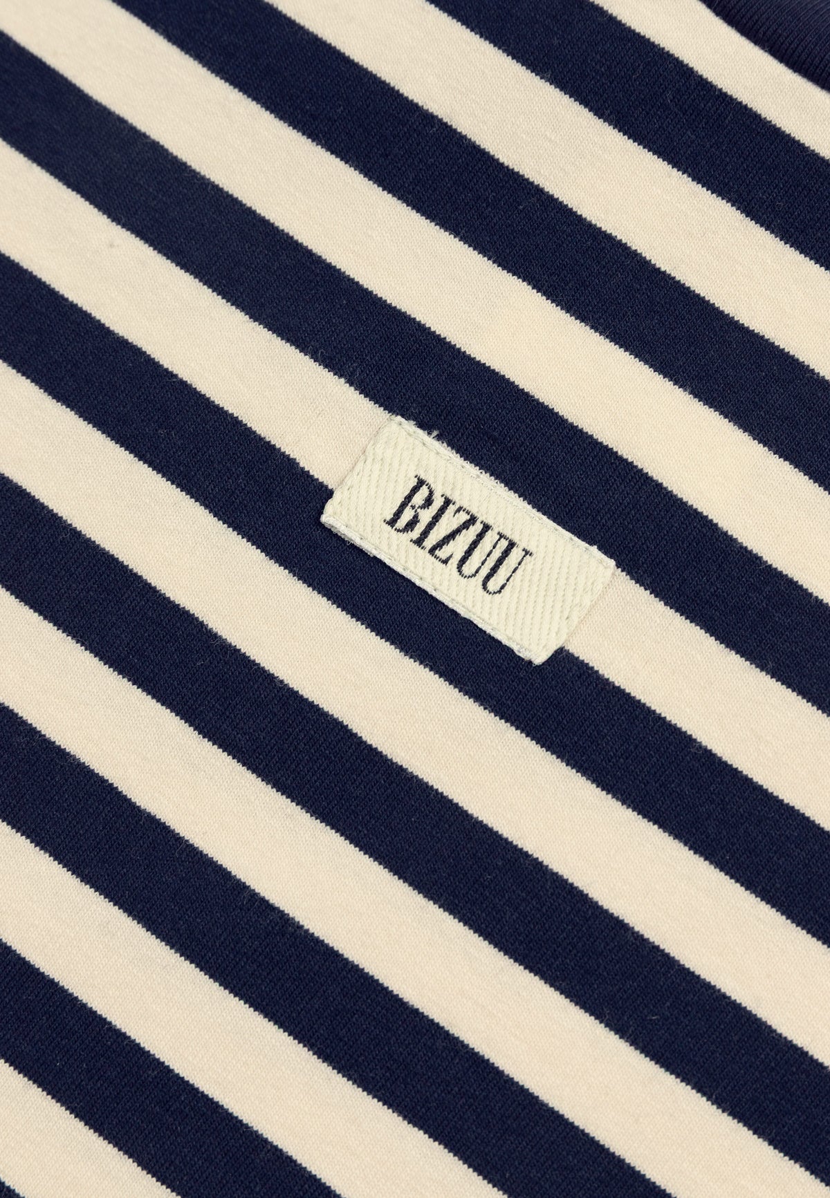 Close-up of the label on the front of the TISHALLY T-shirt in navy blue and cream stripes.