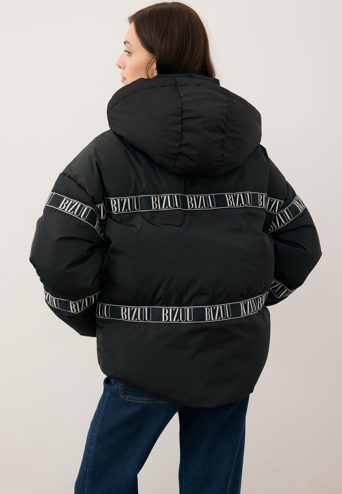 Model standing with her back turned in the TOKYO winter jacket with a branded stripe.