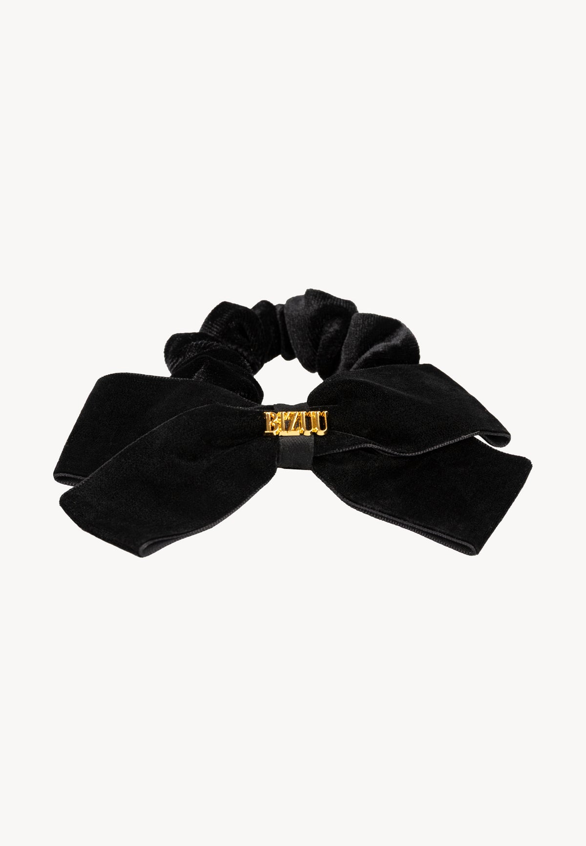 Close-up of the black velvet VELOURA scrunchie with bow and gold lettering.
