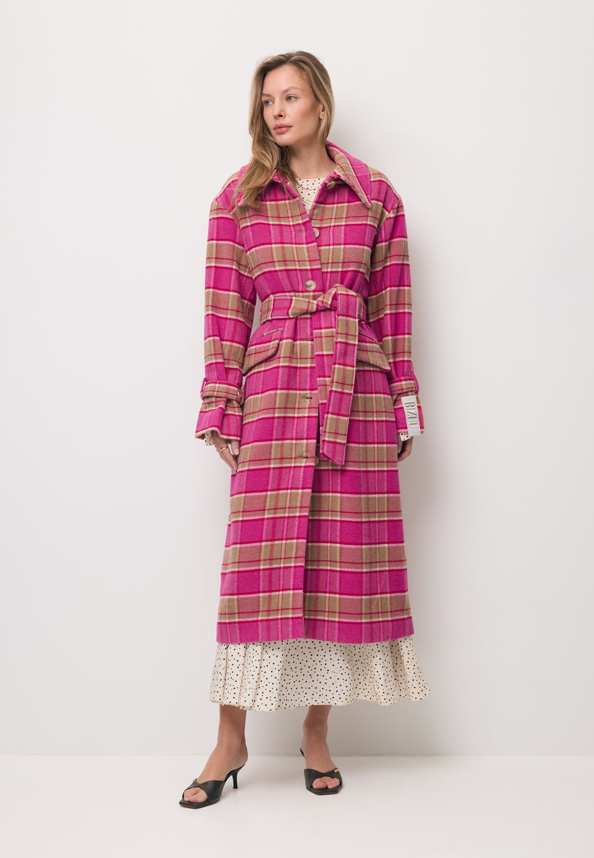 Close-up of the logo label on the sleeve of the pink WIVINA checked coat.