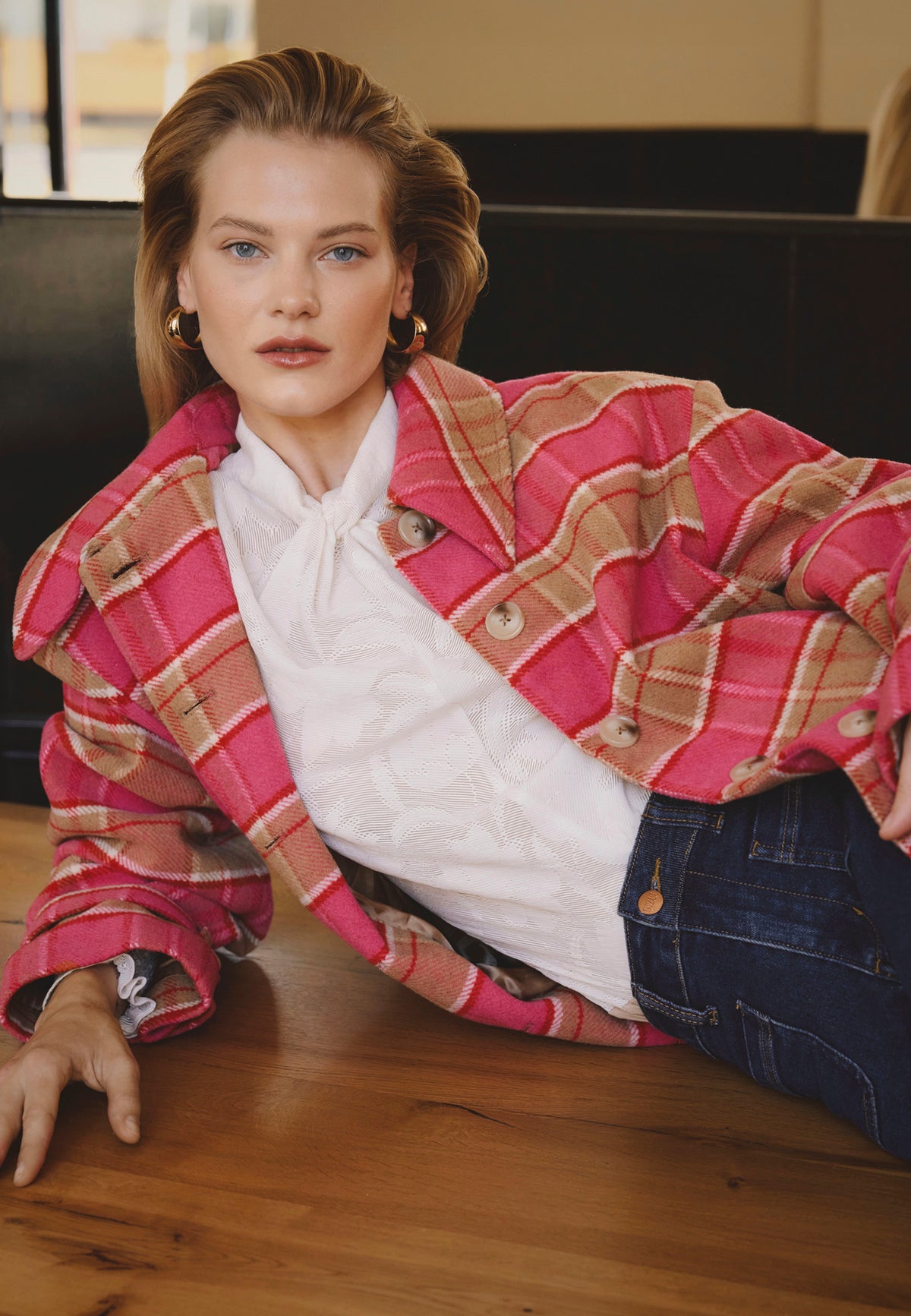 A model wearing a pink WIVINA checked coat with a logo on the sleeve.