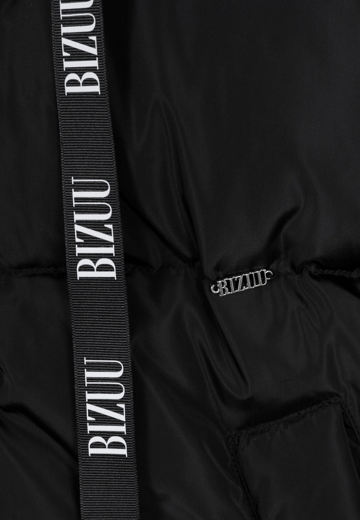 Close-up of the gold logo and branded drawstrings on the front of the black YOKO jacket.