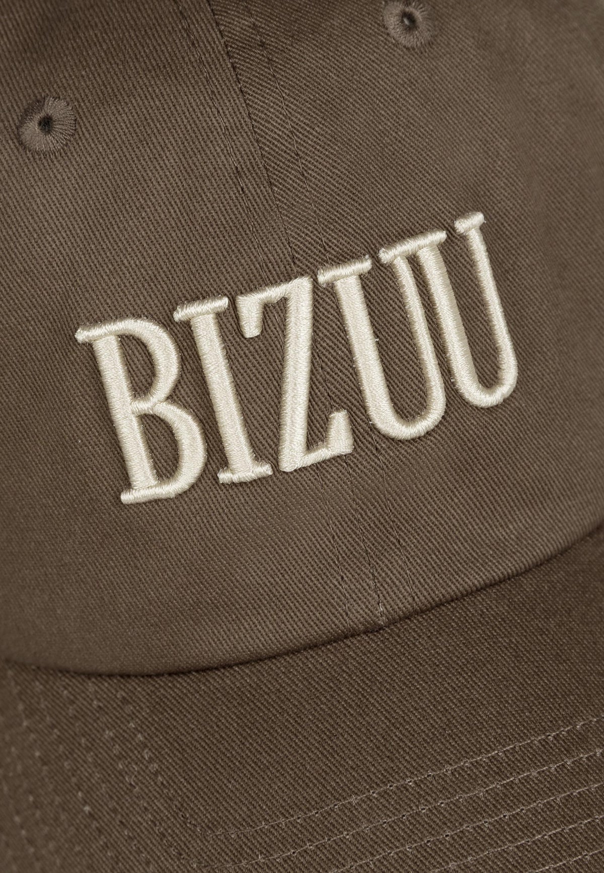 Close-up of the embroidered logo on the front of the brown ZANE cap.