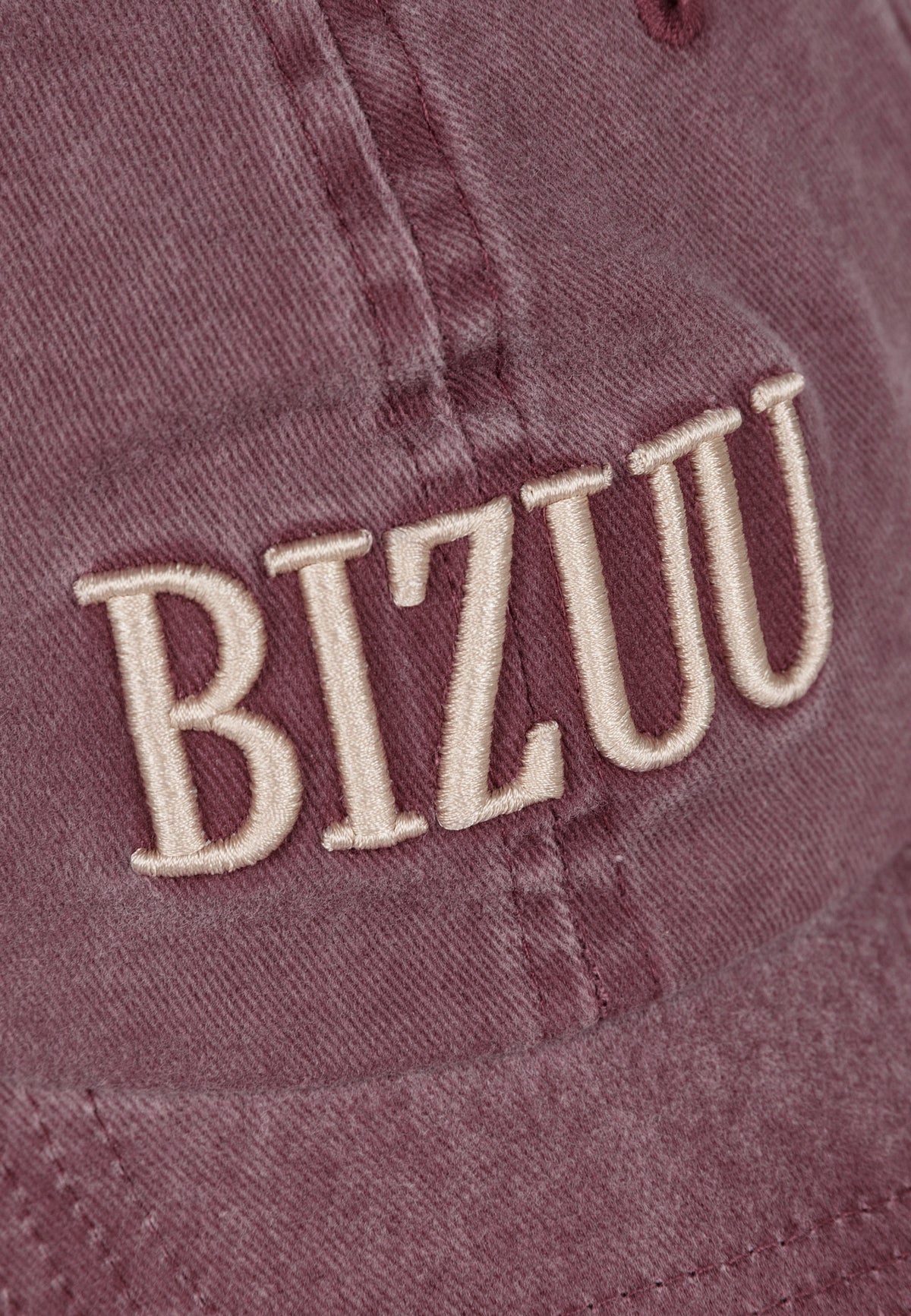 Close-up of the embroidered logo on the front of the burgundy ZANE cap.