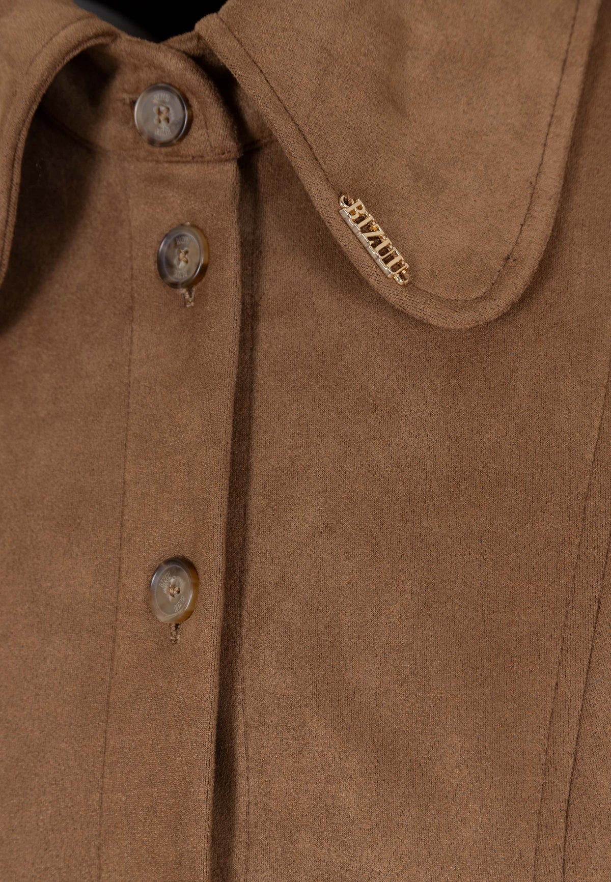 Close-up of the golden letters on the collar of the brown suede ZORELLE dress.