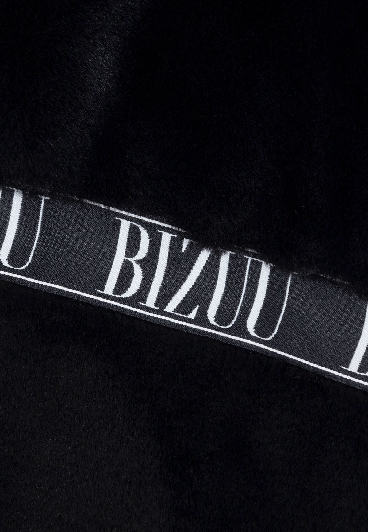 Close-up of the black logo tape on the GREGORIA faux fur coat.