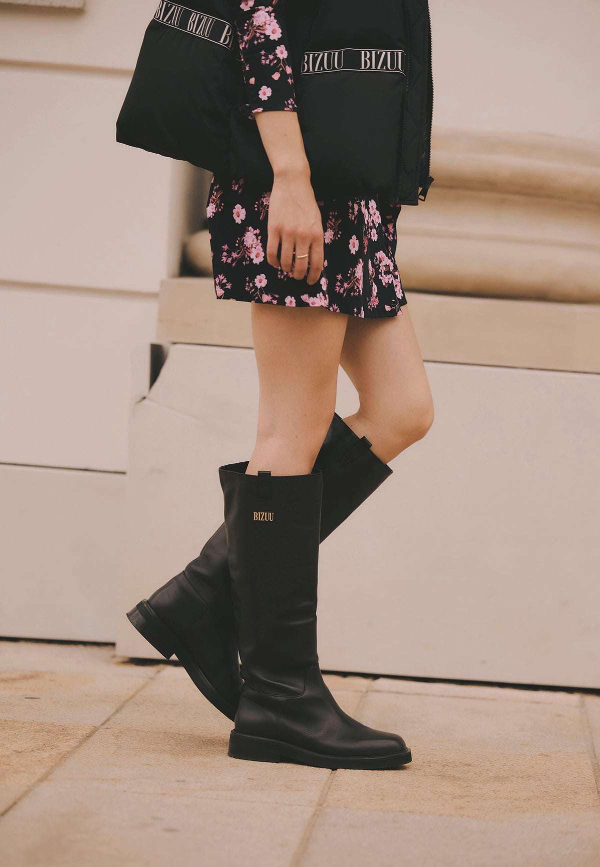 Model walking down the street, close-up of her legs in black leather CALYX boots.