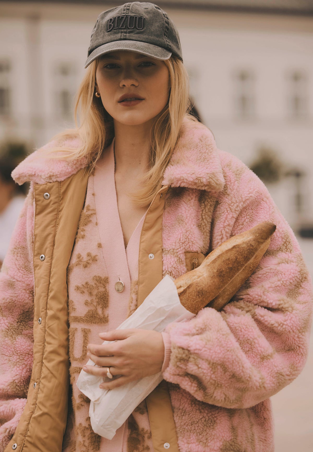 Model holding baguettes, styled in the TEDDY fleece jacket and the ZANE cotton cap.