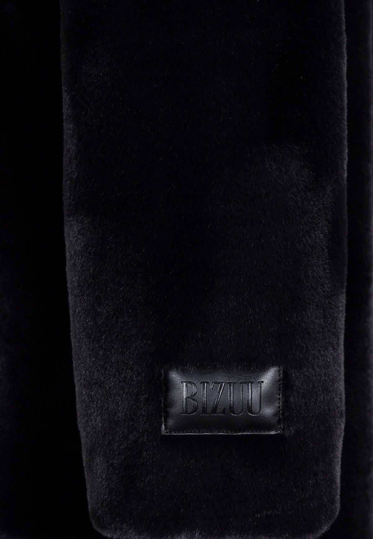 Close-up of the embossed logo on the sleeve of the black ROMA coat.